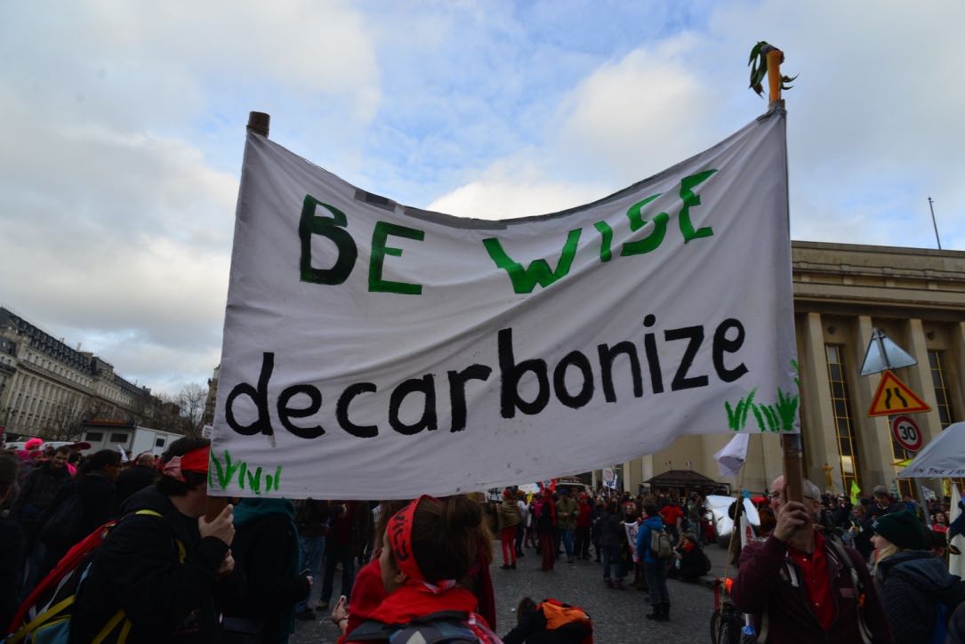 Picture of protestors holding a banner spelling "Be wise, decarbonize"