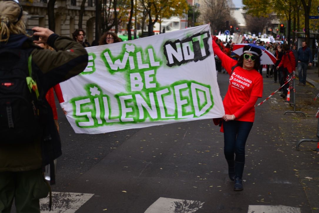 Picture of protestors holding a banner spelling "We will not be silenced"